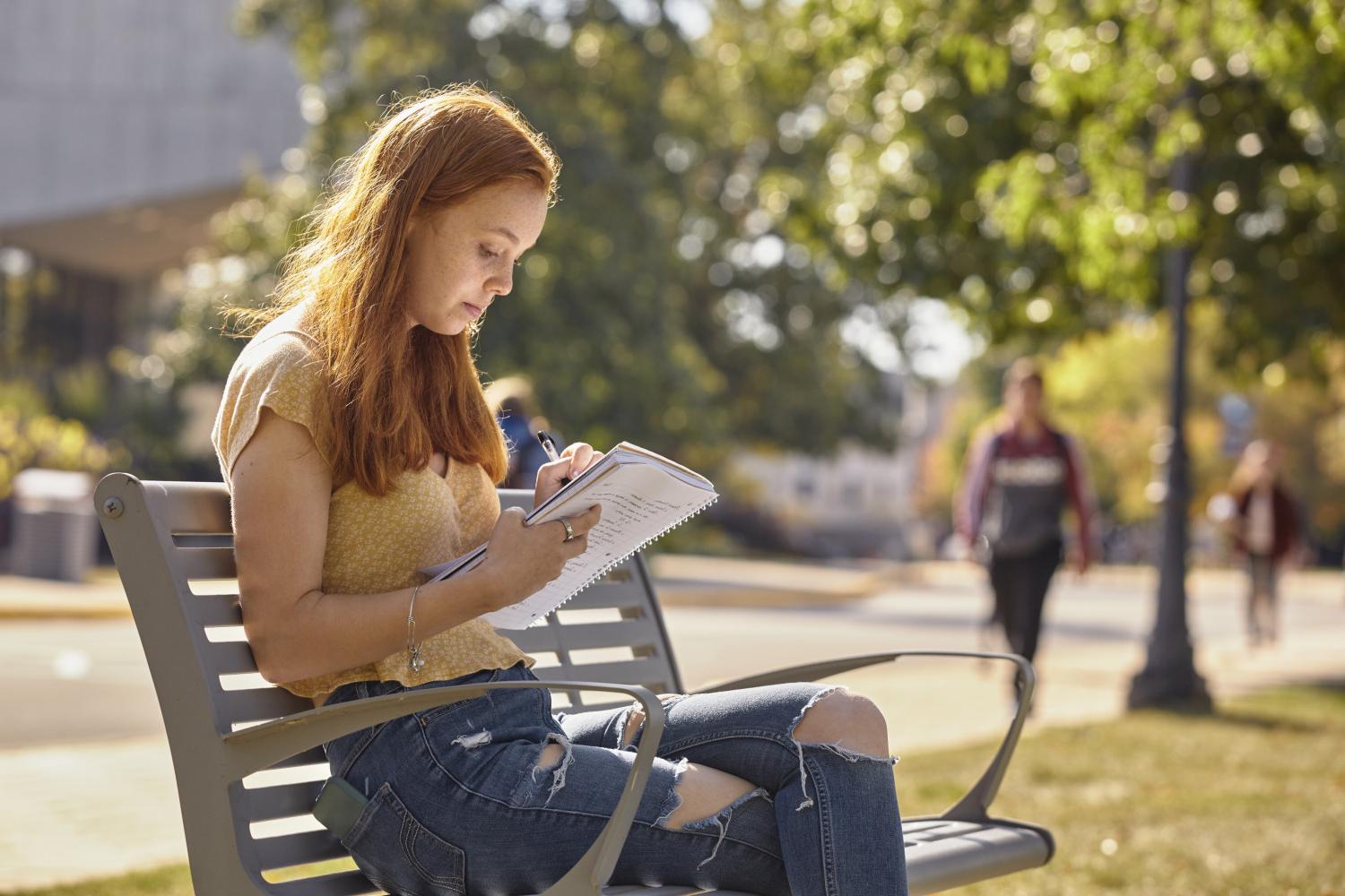 一位<a href='http://ymnx.ngskmc-eis.net'>全球十大赌钱排行app</a>学院的学生在校园里的长椅上读书.